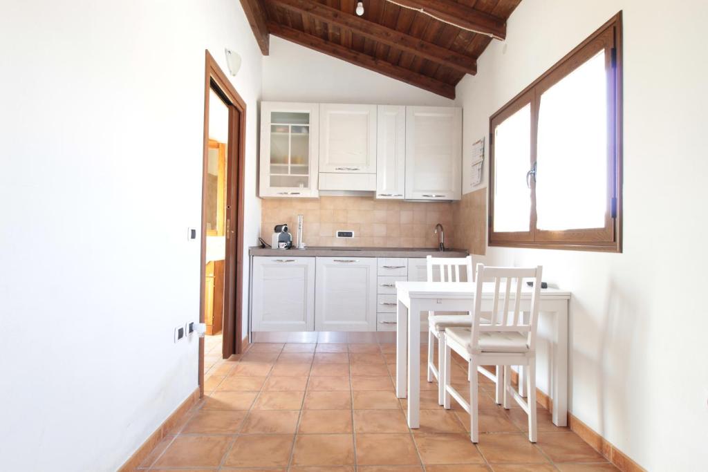塞拉尔朱斯Appartamento Angela的厨房配有白色橱柜和桌椅