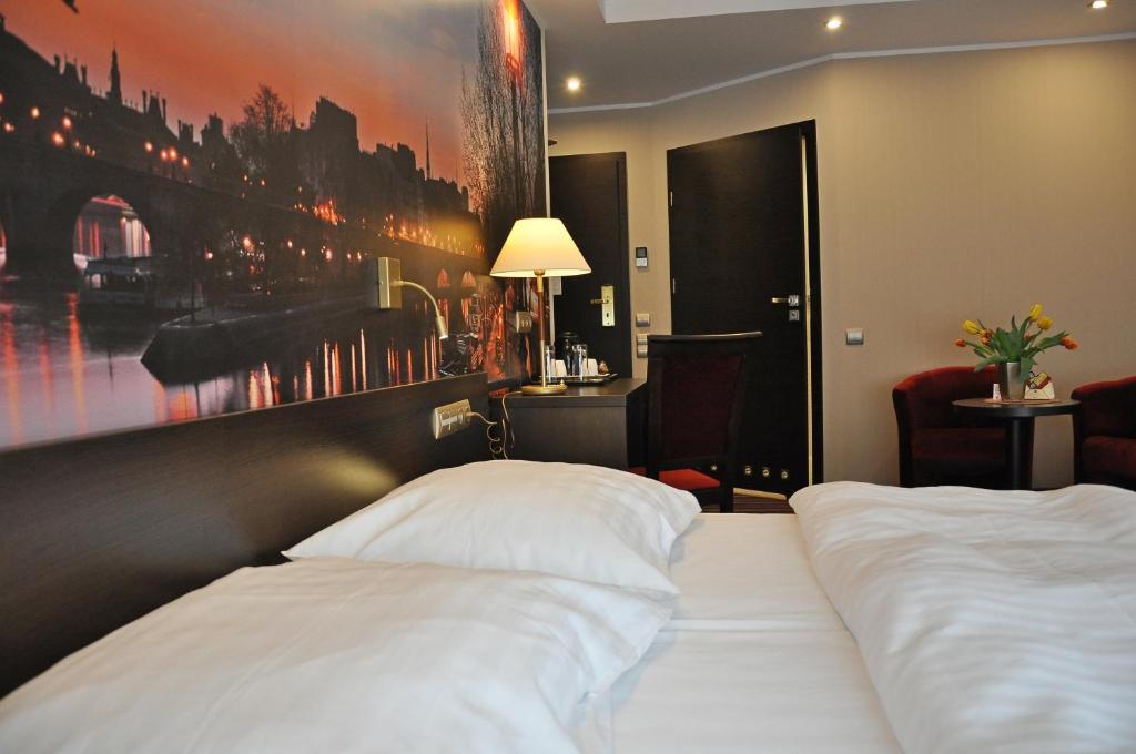 新托梅希尔阿奇姆酒店的酒店客房设有一张床,墙上挂有绘画作品