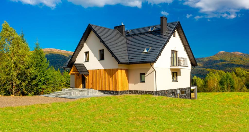 韦特利纳Pod Wielką Zalesioną Górą的绿色山丘上一座黑屋顶的房子