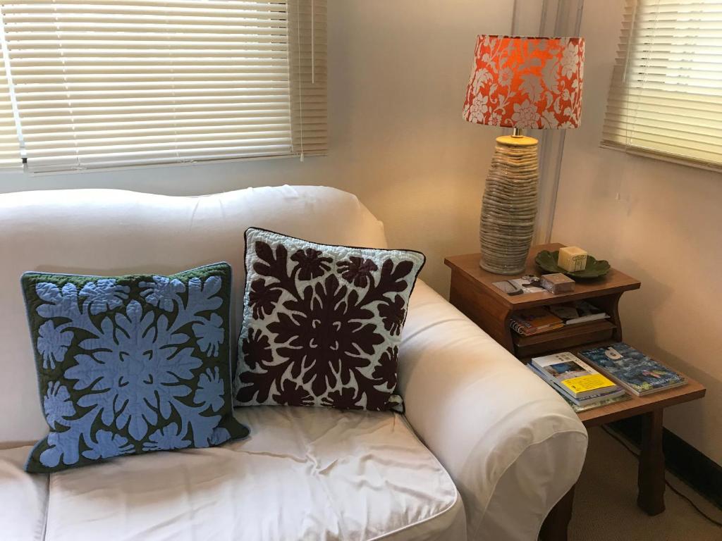 宜野湾市Old American House K-113的配有枕头的白色沙发以及带台灯的桌子