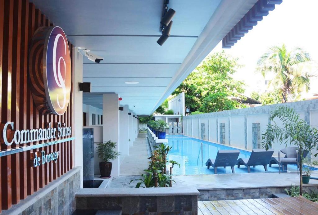 长滩岛Commander Suites de Boracay的一座带游泳池的建筑,上面有标志