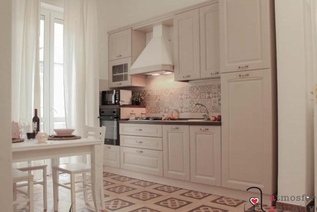 卡利亚里CASACRIZIA的厨房配有白色橱柜、桌子和柜台。