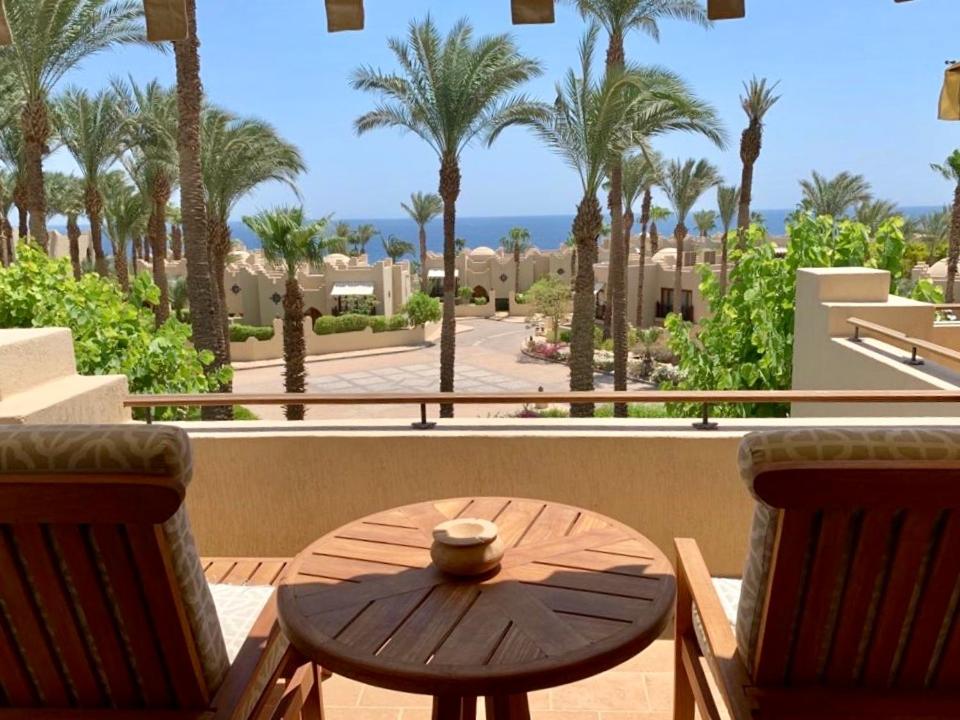 沙姆沙伊赫Elegant Apartment in a Luxury Resort的棕榈树阳台的桌椅
