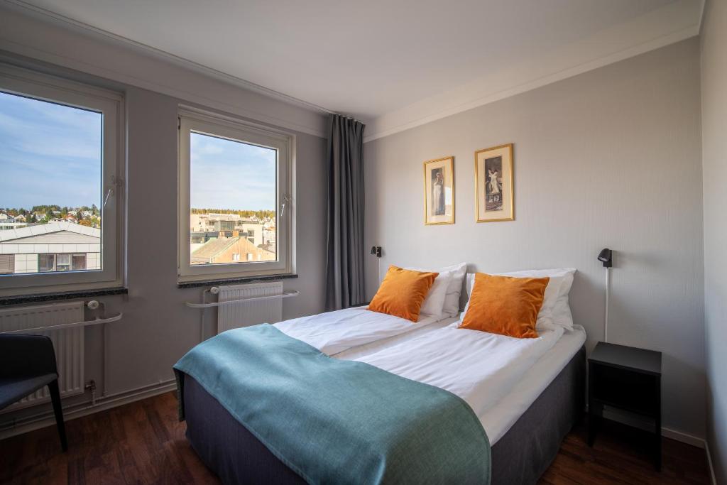 特罗姆瑟阿马利亚入住酒店的一间卧室配有一张大床和两个橙色枕头