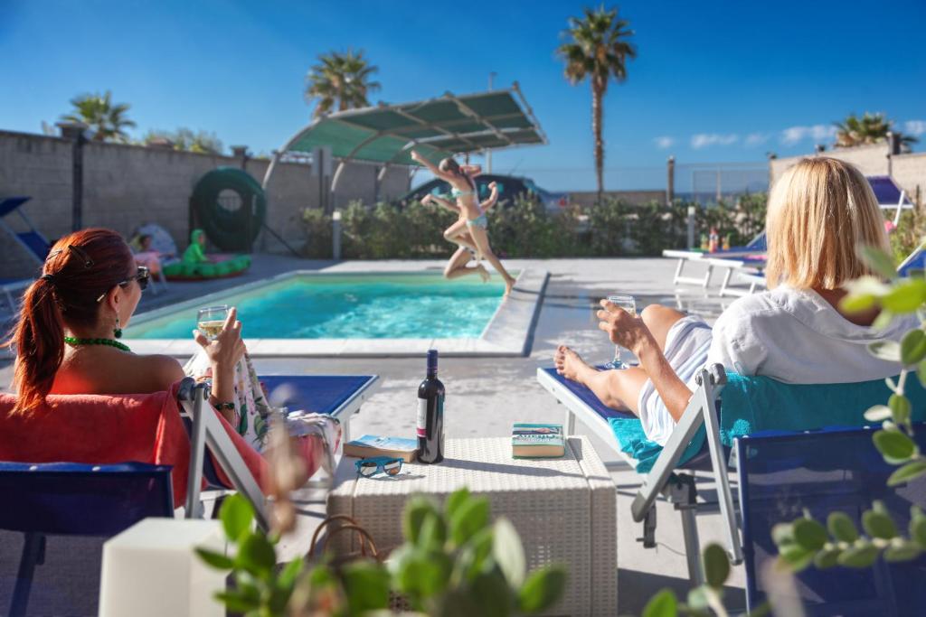 卡普多兰多Terraces d'Orlando - Family Apartments with Sea View and Pool的一群人坐在游泳池边的椅子上