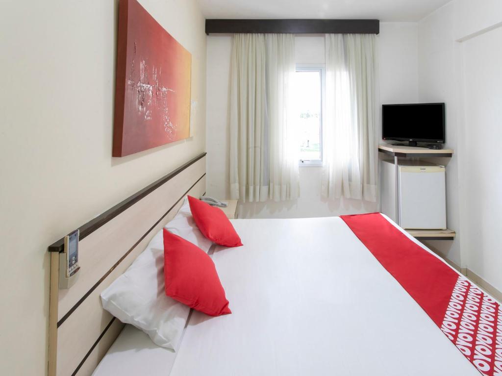 圣若泽杜斯坎普斯Polo Hotel的卧室配有带红色枕头的大型白色床