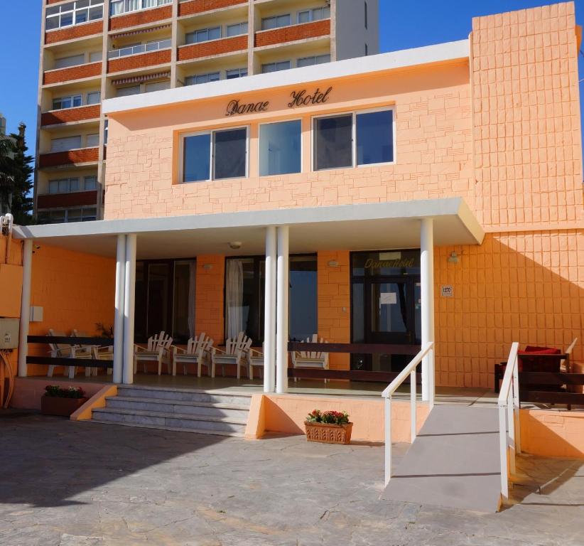 皮里亚波利斯Hotel Danae的一座橙色砖砌建筑,前面配有桌椅