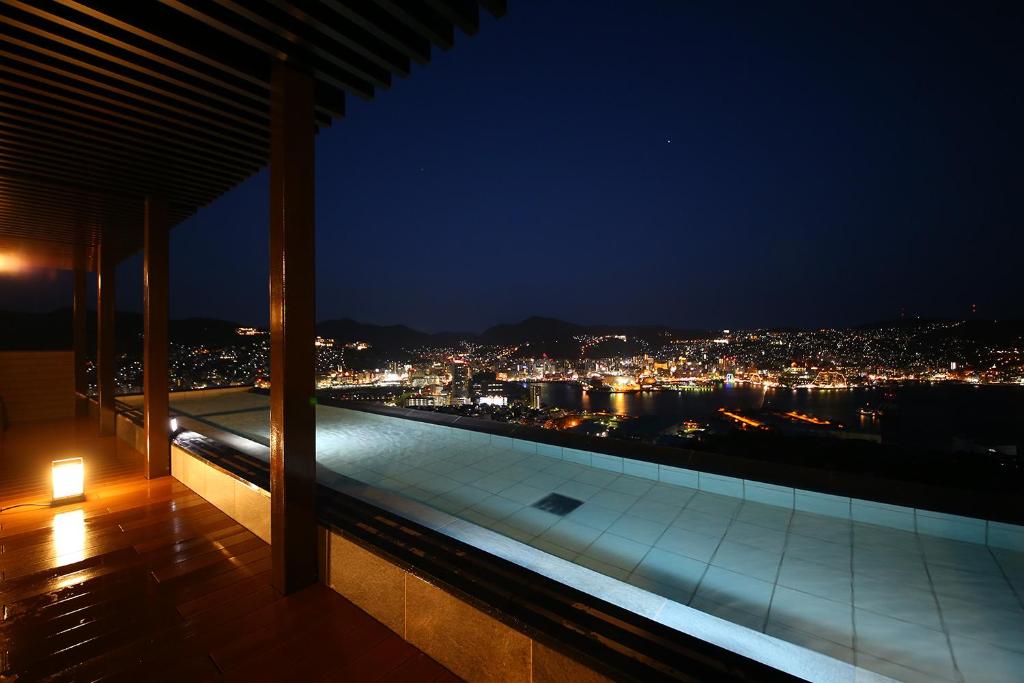 长崎Ooedo Onsen Monogatari Nagasaki Hotel Seifu的建筑在晚上可欣赏到城市美景