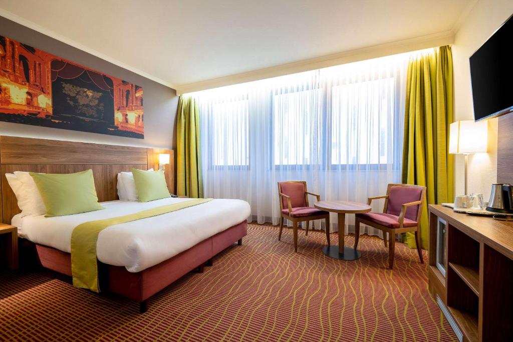 安特卫普Hotel Opera Antwerpen Centrum的酒店客房带一张床、一张桌子和椅子