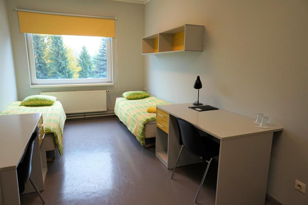 塔尔图市区旅舍的一间卧室设有两张床、一张桌子和一个窗口。