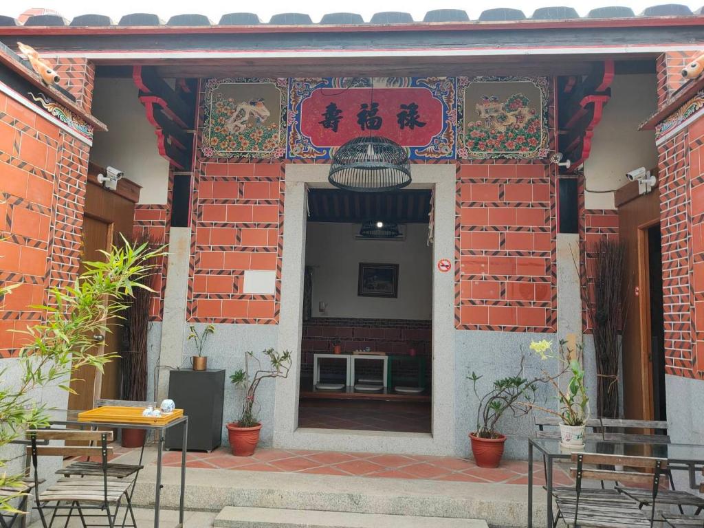 金宁乡喜樂居的一座配有桌椅的建筑的入口