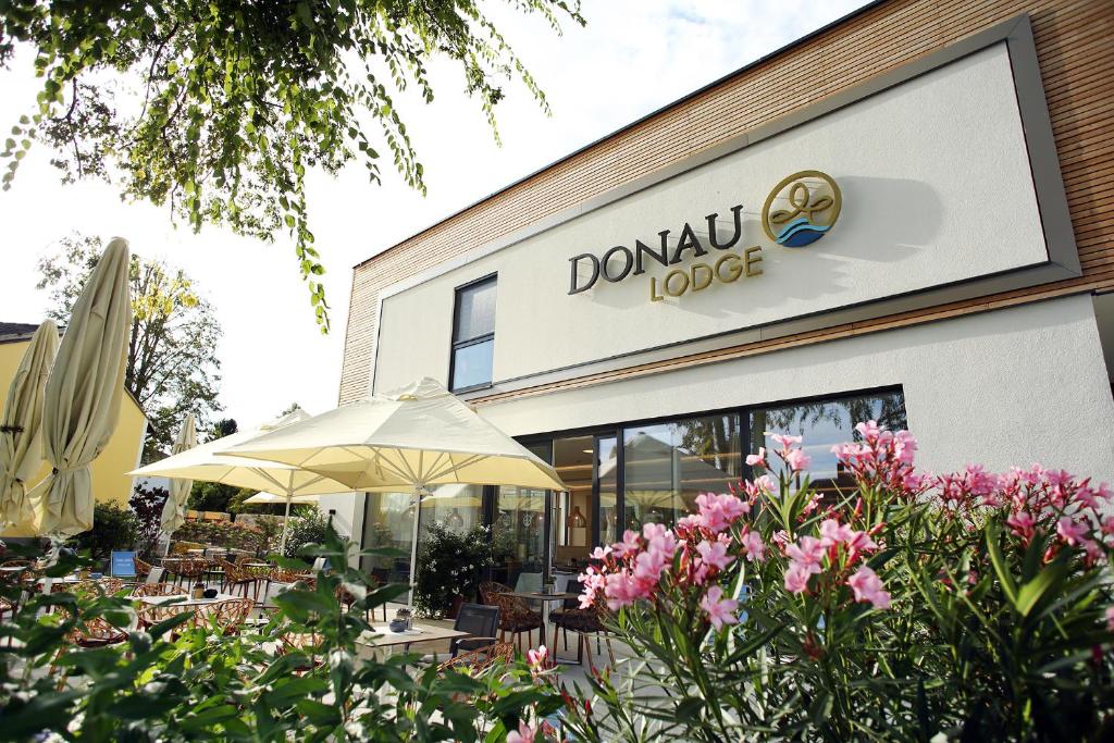多瑙河畔伊布斯Donau Lodge的一间设有遮阳伞和鲜花的餐厅