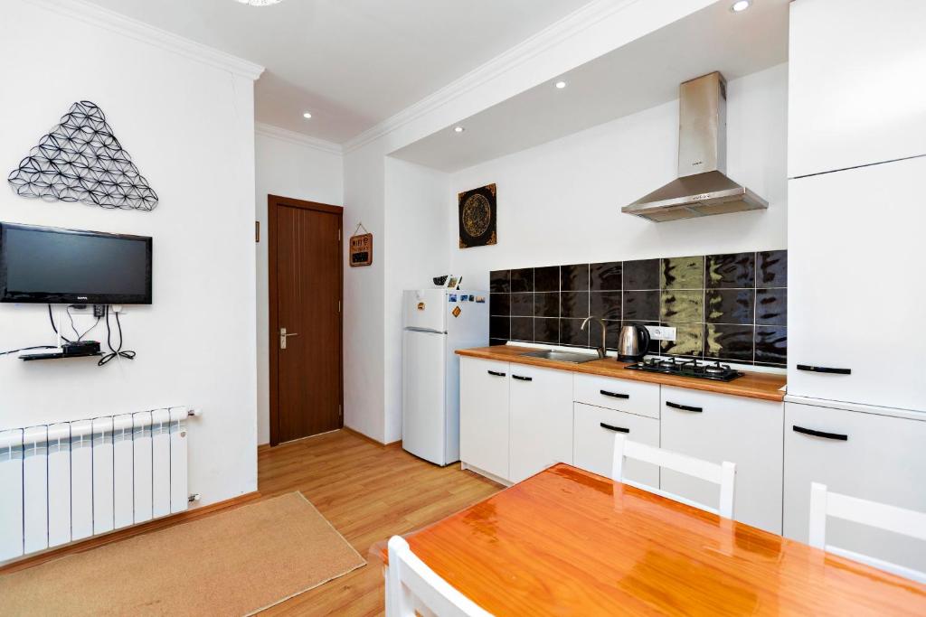 第比利斯31 Toidze Apartment的厨房配有白色橱柜和平面电视。