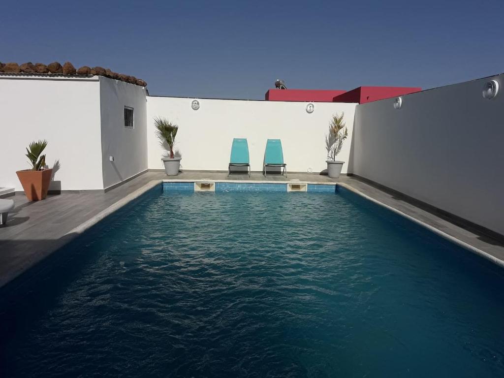 PoponguineAfrican Jaja villa Piscine-Climatisation的一座游泳池旁设有两把蓝色椅子