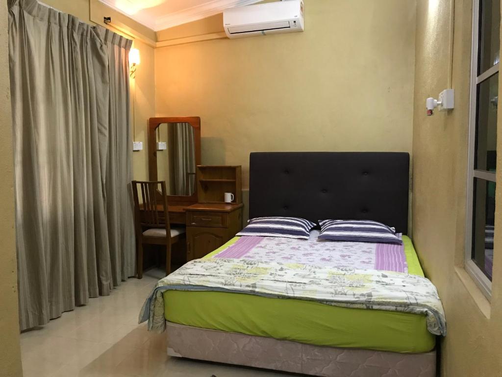Pasir MasWan Guest House的一间卧室配有一张床和一张桌子及椅子