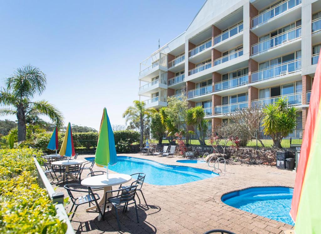 尼尔森湾滨海度假村的游泳池旁的酒店设有桌椅