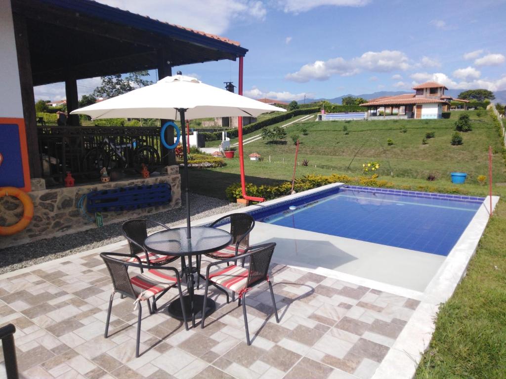 蒙特内哥罗Casa Finca La Pintada的游泳池旁配有遮阳伞的桌椅