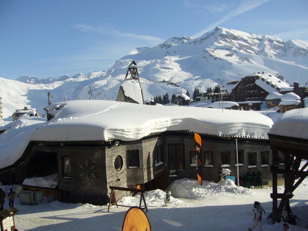 阿沃里亚兹Fontaines Blanches 320的一座被雪覆盖的建筑,背景是一座山