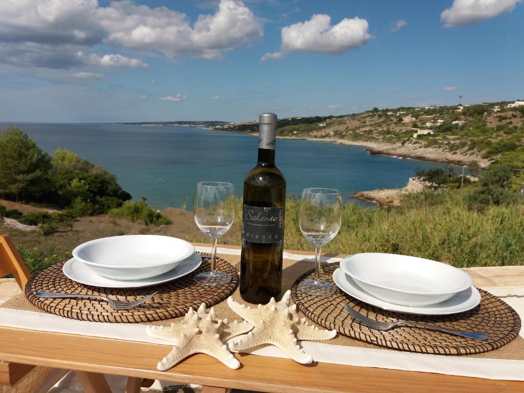 莱乌卡Appartamenti Baia Azzurra的一张桌子,上面放两个盘子和一瓶葡萄酒