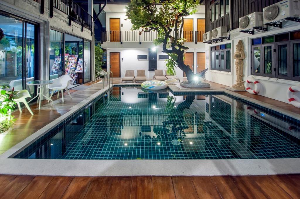 清迈Sathu Hotel的一座带桌椅的室内游泳池
