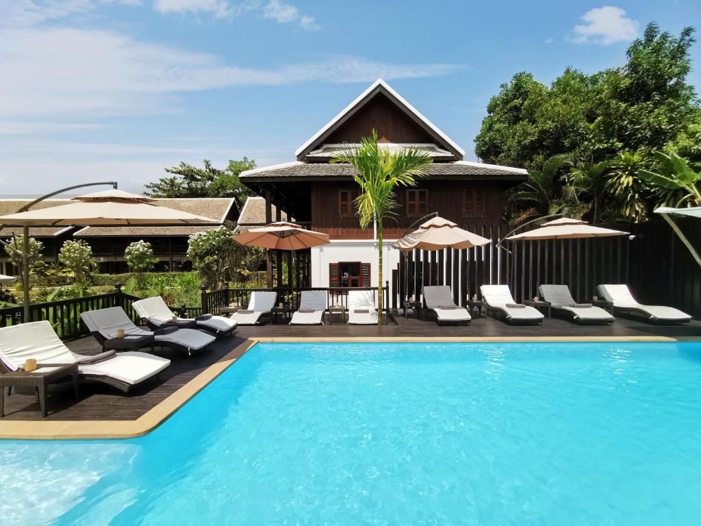琅勃拉邦琅勃拉邦保护区酒店的一个带躺椅的游泳池以及一座房子