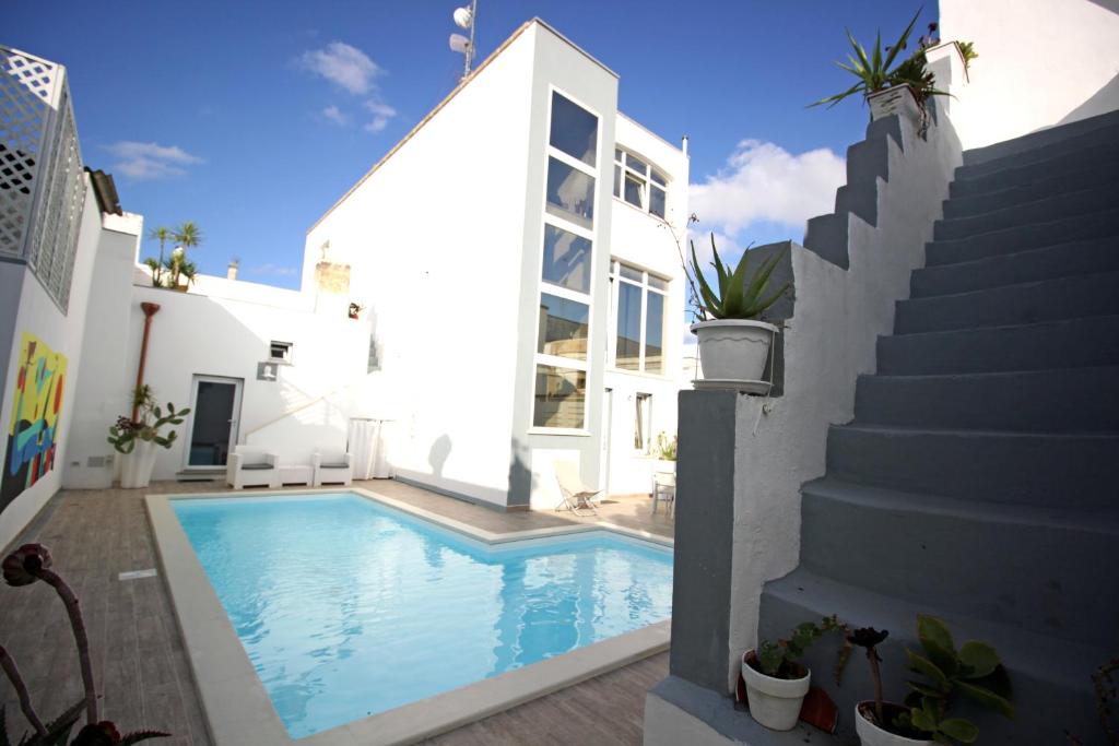 拉卡莱Salentuosi Camere的白色房子旁的游泳池,设有楼梯