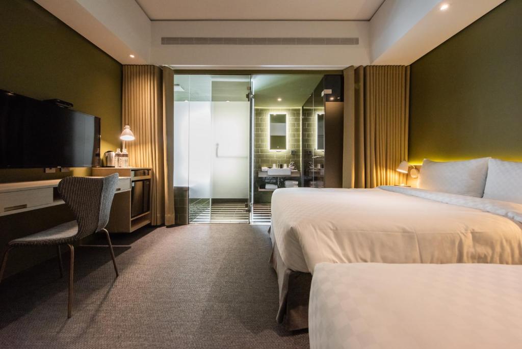 台中市城市漫游行旅的酒店客房设有两张床、一张桌子和一台电视。