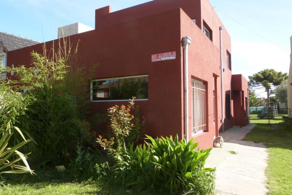 内科切阿Duplex en Necochea的一座红色的建筑,外面坐着一只猫