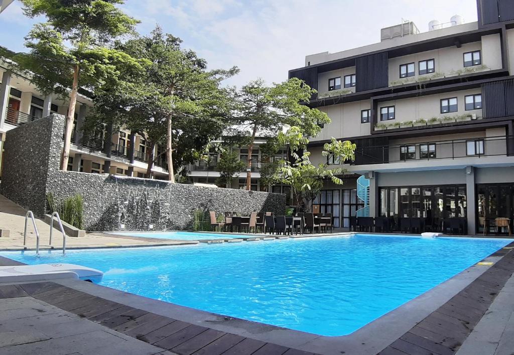 库宁岸Grand Cordela Hotel AS Putra Kuningan的大楼前的大型蓝色游泳池