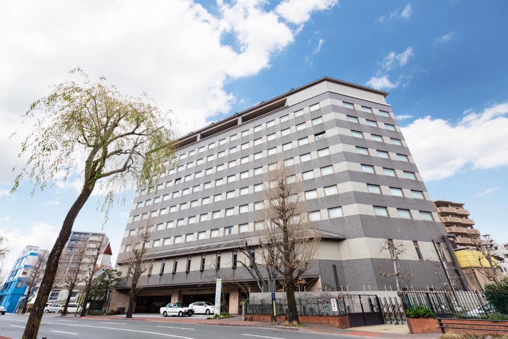 熊本Ark Hotel Kumamotojo Mae -ROUTE INN HOTELS-的街道边高大的白色建筑