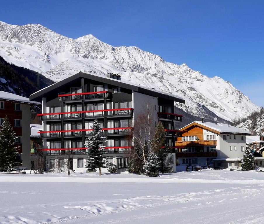萨斯阿尔马格尔Hotel Alpenhof的雪覆盖的山前的建筑物