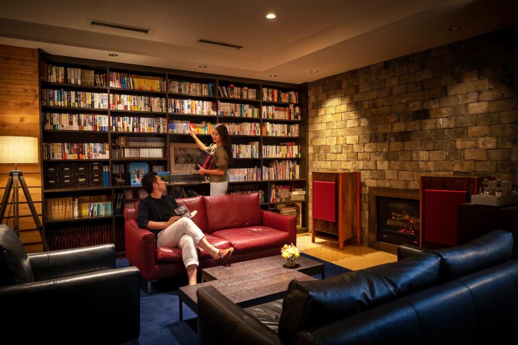 函馆康考迪亚别墅Spa度假酒店的坐在沙发上的男人站在图书馆里的女人