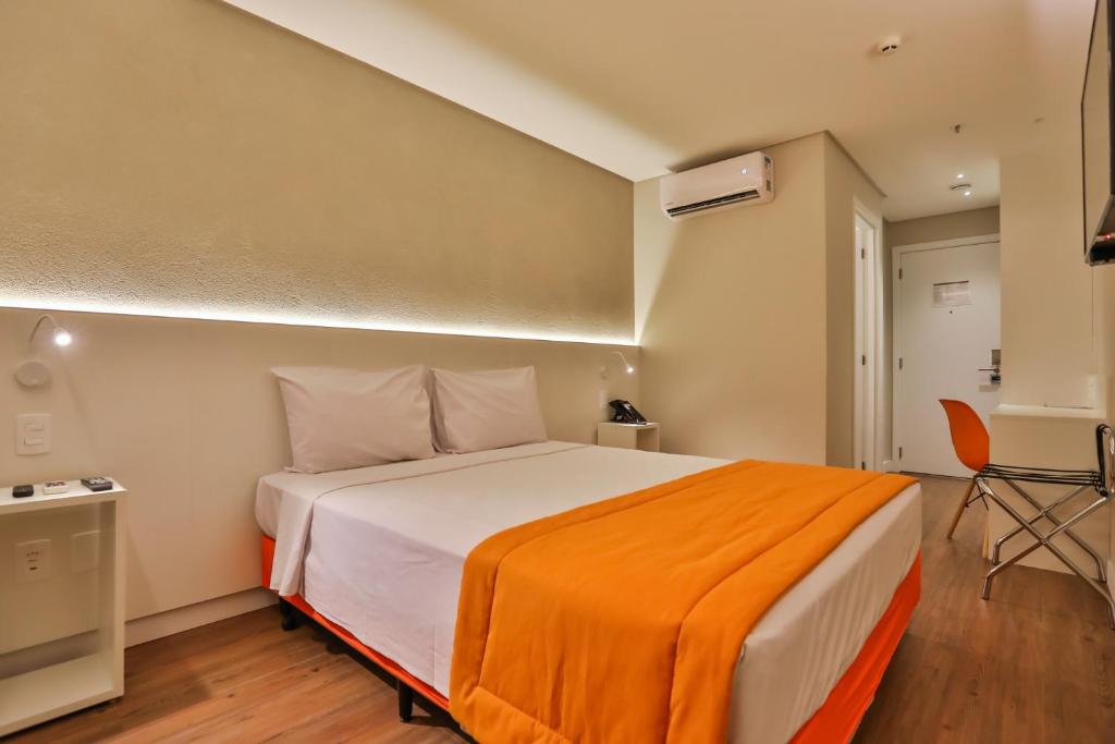 塞拉Go Inn Serra的一间卧室配有一张带橙色毯子的大床