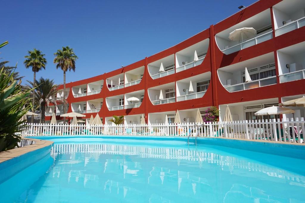 英格兰海滩厄瓜多尔公寓的一座红色建筑前的带游泳池的酒店