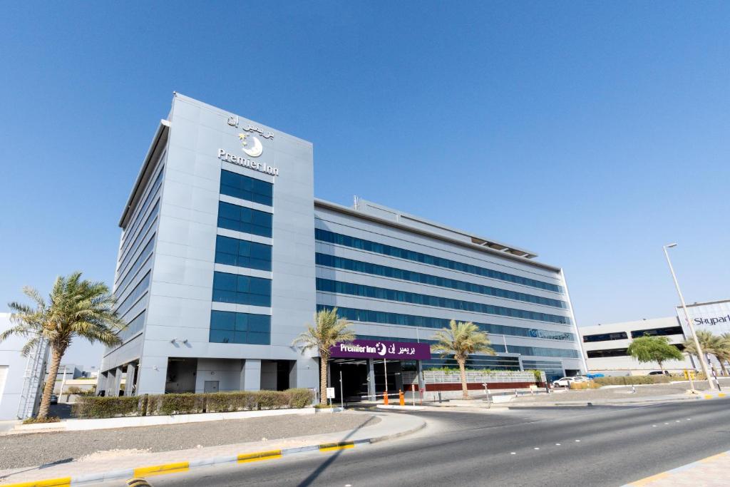 阿布扎比Premier Inn Abu Dhabi Airport Business Park的一座白色的大建筑,前面有棕榈树