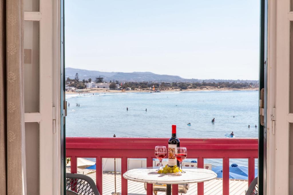 纳克索乔拉帕拉迪亚酒店的一张桌子,上面放着一杯葡萄酒,享有海滩美景