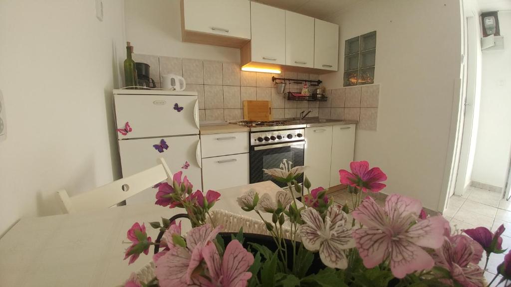 Draga BašćanskaApartman Goga的厨房配有白色冰箱和粉红色的鲜花