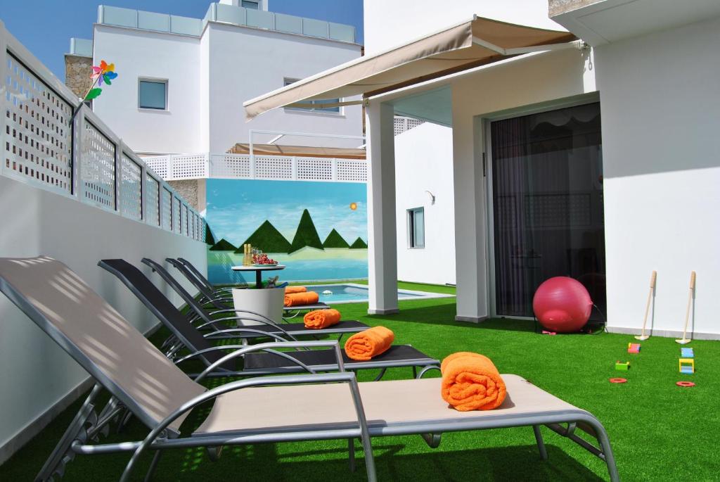 莫甘Big Villa Tauro with Private Heated Saltwater Pool & jacuzzi & BBQ & Game Room的阳台配有椅子和绿色草坪。