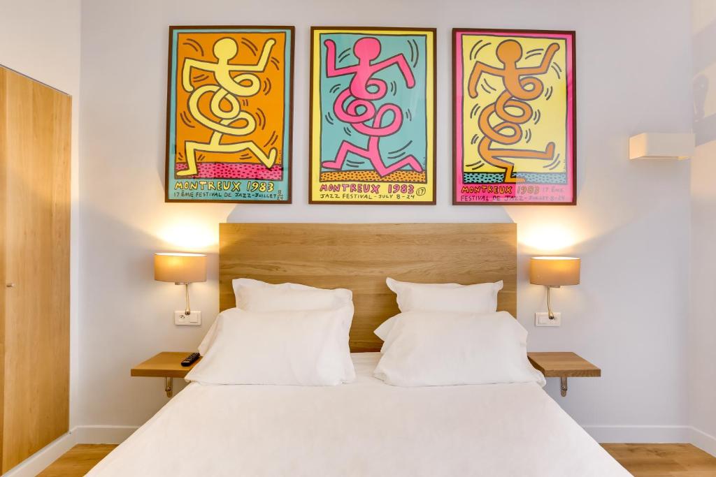 巴黎里切里尔卢浮酒店的一间卧室配有一张床,墙上有三幅画作