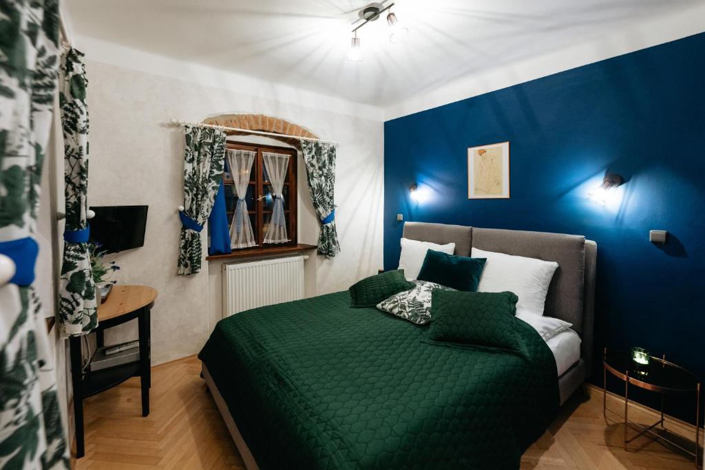 捷克克鲁姆洛夫罗曼蒂克精品酒店的一间卧室配有一张绿色的床和蓝色的墙壁