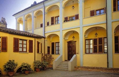 Cocconato隆卡德马特勒蒂酒店的一座黄色的大建筑,设有楼梯和门