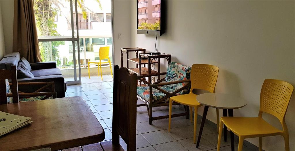 乌巴图巴Apartamento Ubatuba的客厅配有椅子、桌子和电视