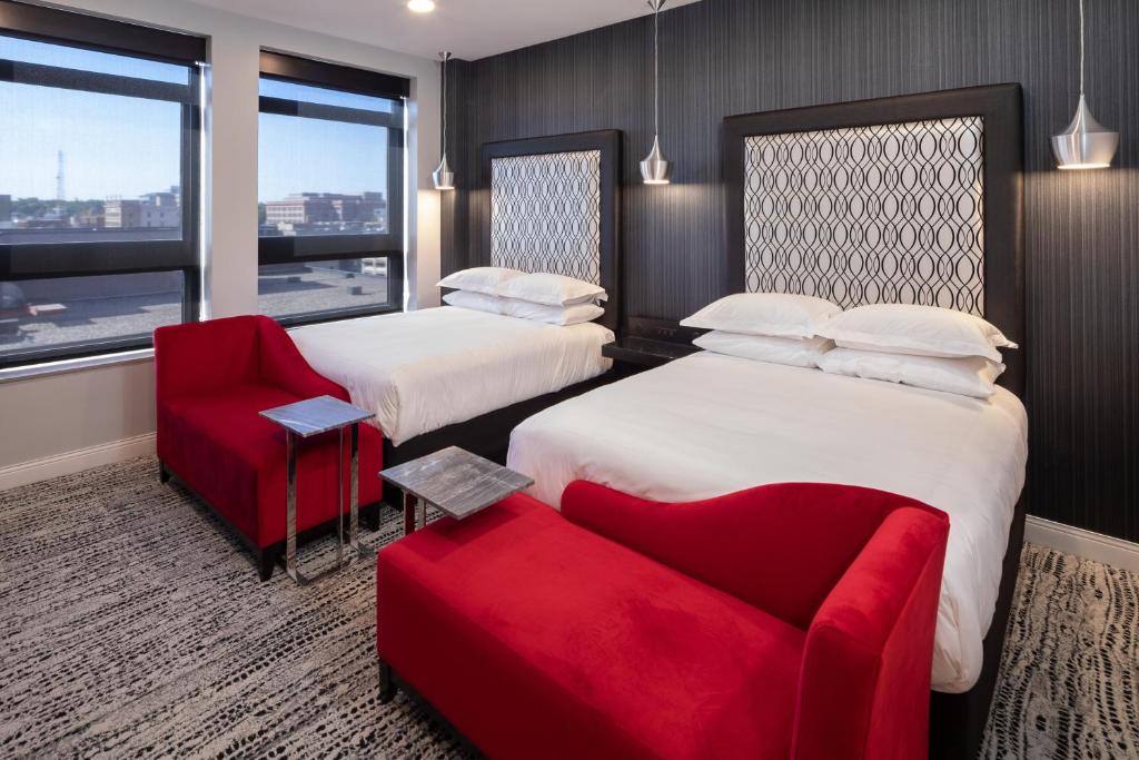 苏福尔斯Hotel On Phillips的酒店客房,设有两张床和一张红色椅子