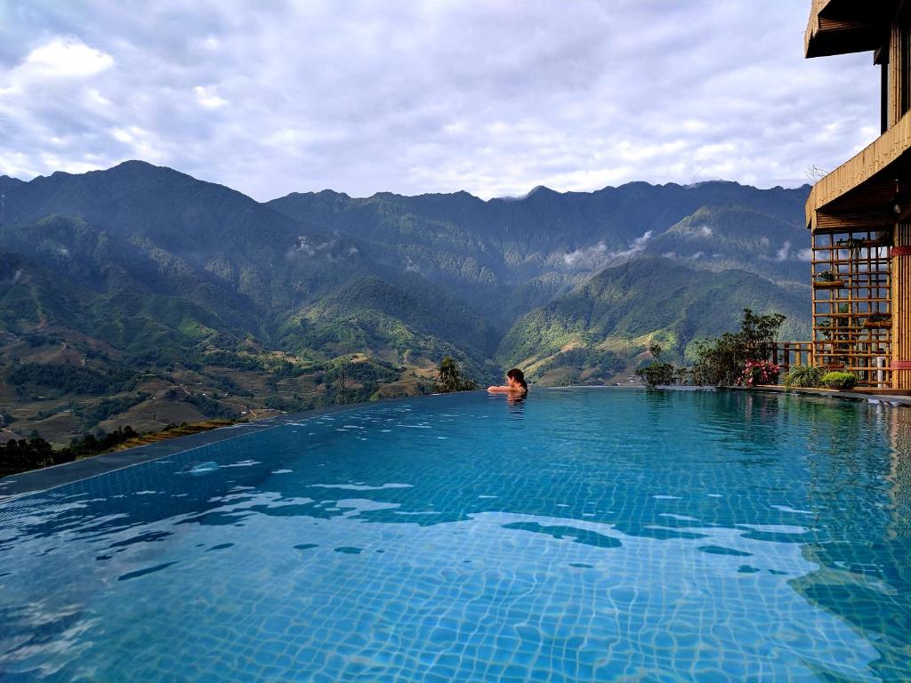 萨帕萨巴克莱之家山区度假酒店的背景为山脉的无边游泳池里的人