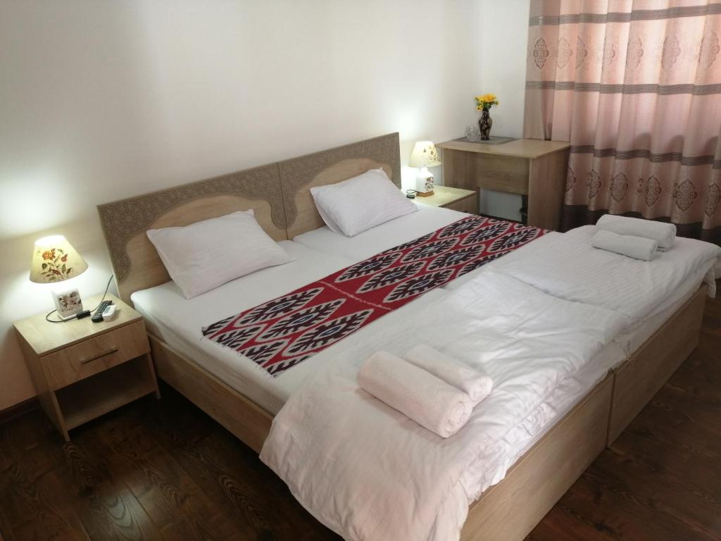 布哈拉Anis-Pari Hotel的卧室配有一张带白色床单和枕头的大床。