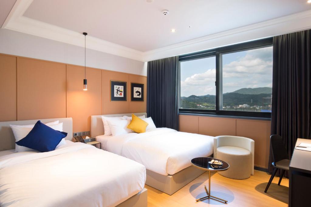 晋州市Brown Dot Hotel Jinju的酒店客房设有两张床和窗户。