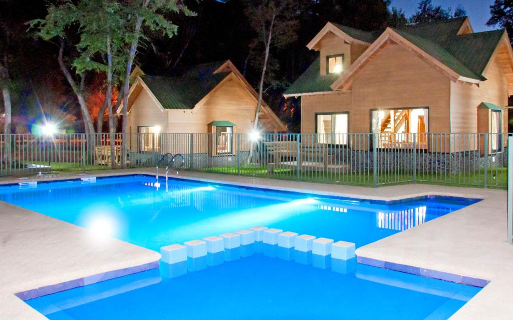 拉斯特朗卡斯Cabanas y Lodge Los Hualles的夜间在房子前面的游泳池