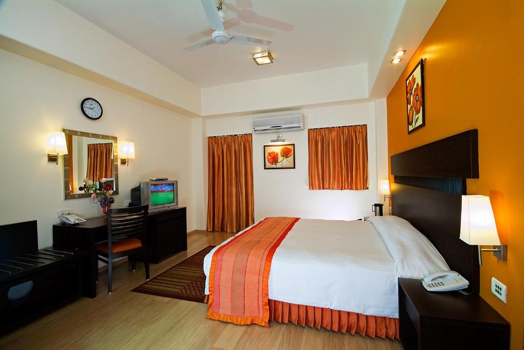 孟买Chateau Windsor Hotel - Marine Drive的酒店客房配有一张床、一张书桌和一台电视。