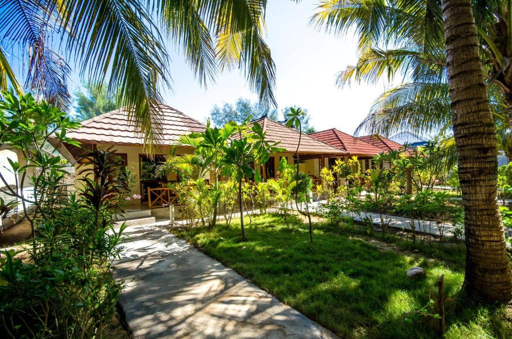 吉利美诺梦幻小屋旅馆的一座棕榈树度假村,位于一座建筑前