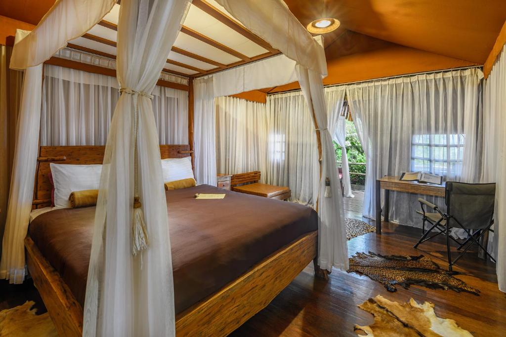 贾蒂卢维桑吉里 - 高山露营营地的一间卧室配有一张天蓬床和一张书桌
